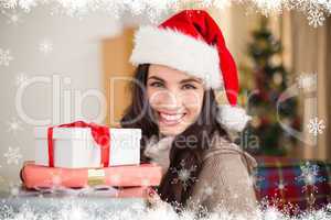 Composite image of festive brunette holding pile of gifts at chr