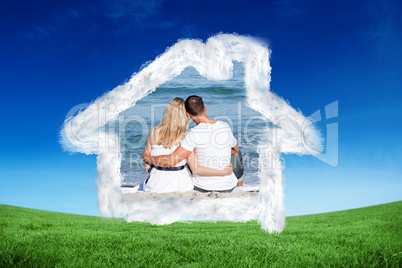 Composite image of affectionate couple sitting on the sand at th