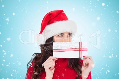 Composite image of festive brunette holding a gift