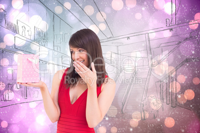 Composite image of festive brunette holding a gift bag