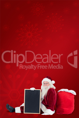 Composite image of santa sits leaned on his bag with a board