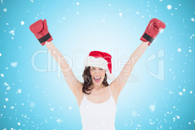 Composite image of festive brunette in boxing gloves cheering