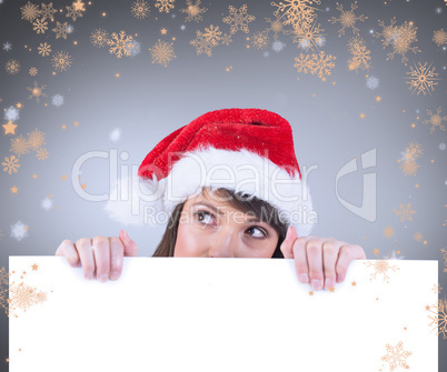 Composite image of festive brunette holding a poster while looki