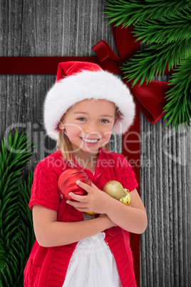 Composite image of cute little girl wearing santa hat holding ba