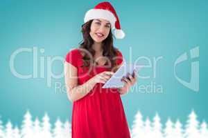 Composite image of festive brunette using her tablet pc