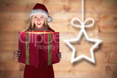 Composite image of festive blonde holding a gift