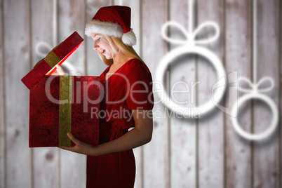 Composite image of festive blonde opening a gift