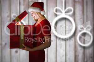 Composite image of festive blonde opening a gift