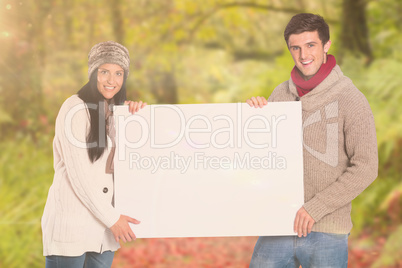 Composite image of young couple holding a poster