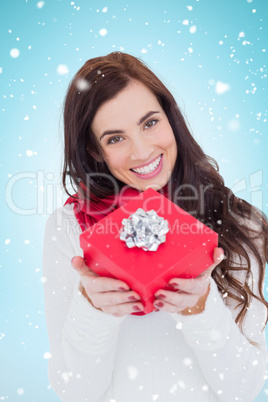 Composite image of happy brunette showing red gift with a bow