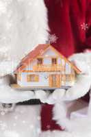 Composite image of santa holds a tiny house in his hands