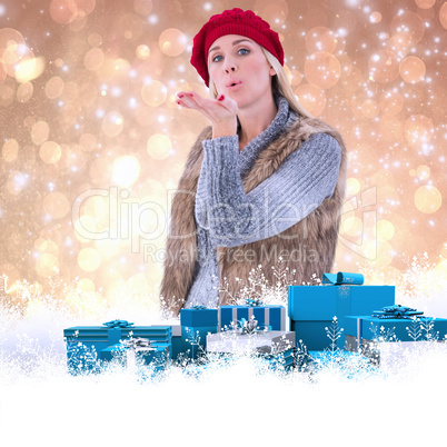 Composite image of blonde in winter clothes blowing kiss