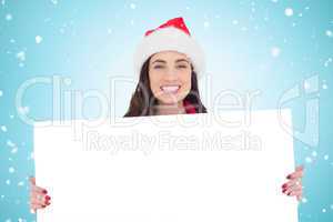 Composite image of smiling brunette in santa hat showing white p