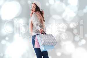 Composite image of brunette keeping a secret and holding shoppin
