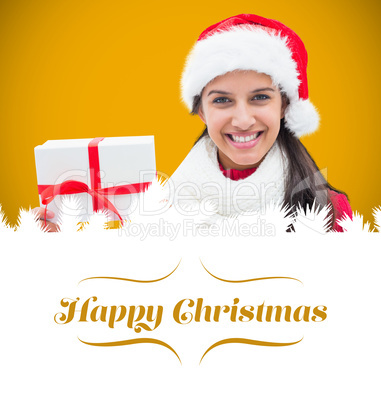 Composite image of festive brunette holding gift