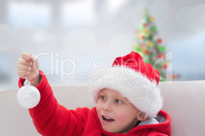 Composite image of cute boy holding bauble