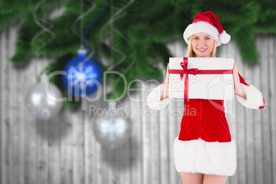 Composite image of festive blonde holding a gift