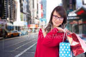 Composite image of happy brunette holding shopping bags