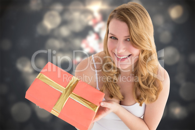Composite image of cute blonde holding a gift