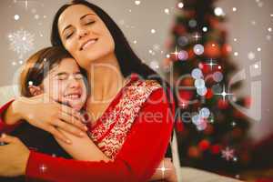 Composite image of festive mother and daughter hugging on couch