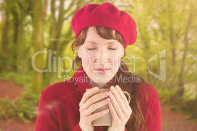 Composite image of woman holding a warm cup