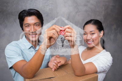 Composite image of happy couple holding house key and leaning on