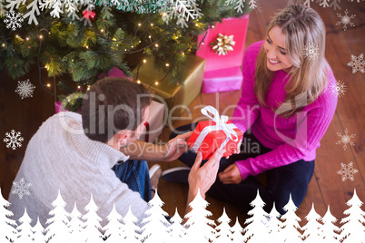 Composite image of sitting couple giving each other presents