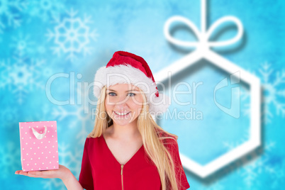 Composite image of festive blonde holding a gift bag