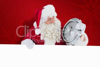 Composite image of santa holding a clock and sign