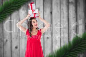 Composite image of happy brunette in red dress holding many gift