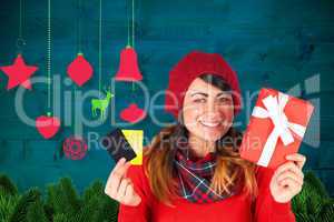 Composite image of smiling brunette holding gift and cards