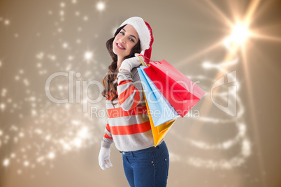 Composite image of festive brunette in winter wear holding shopp