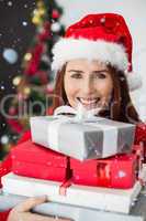 Composite image of festive redhead holding christmas gifts