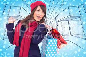 Composite image of happy brunette in winter clothes holding shop