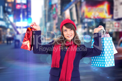 Composite image of pretty brunette holding up shopping bags