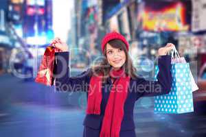 Composite image of pretty brunette holding up shopping bags