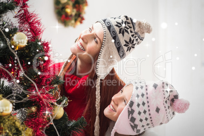 Composite image of mother and daughter decorating christmas tree