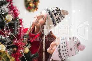 Composite image of mother and daughter decorating christmas tree