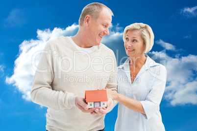 Composite image of happy mature couple with model house