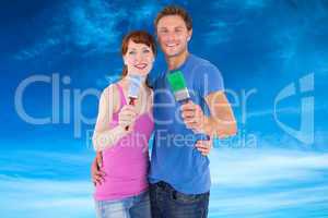 Composite image of couple both holding paint brushes