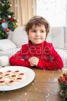Composite image of festive little boy having milk and cookies