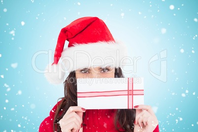 Composite image of festive brunette holding a gift