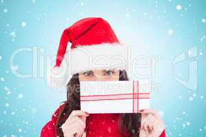 Composite image of festive brunette holding a gift