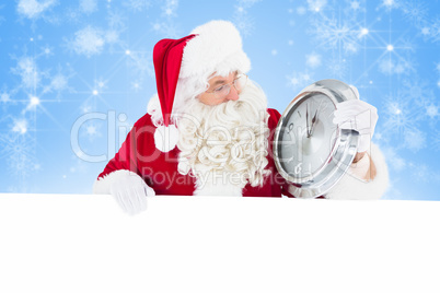 Composite image of santa holding a clock and sign