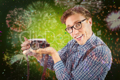 Composite image of geeky hipster holding a retro camera