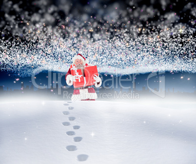 Composite image of santa carrying gifts in the snow