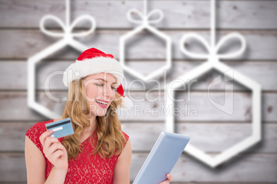 Composite image of festive blonde woman using her credit card an