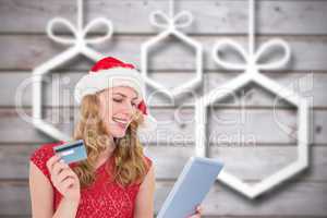 Composite image of festive blonde woman using her credit card an