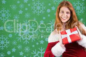 Composite image of festive redhead holding a gift