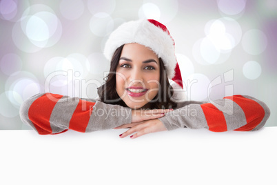 Composite image of beauty brunette in santa hat smiling at camer